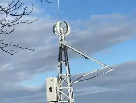 Вітряк на металевій щоглі під синім небом