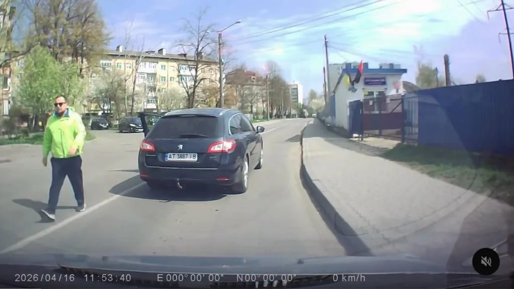 Пішохід переходить дорогу біля чорного автомобіля