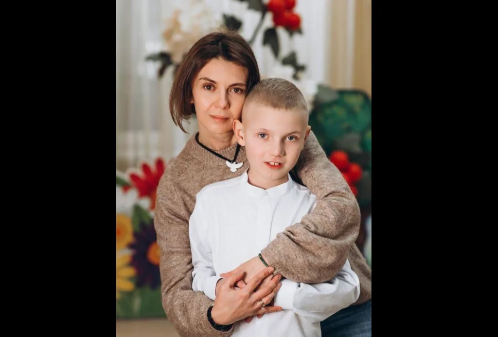 Мама обіймає сина перед яскравими квітами