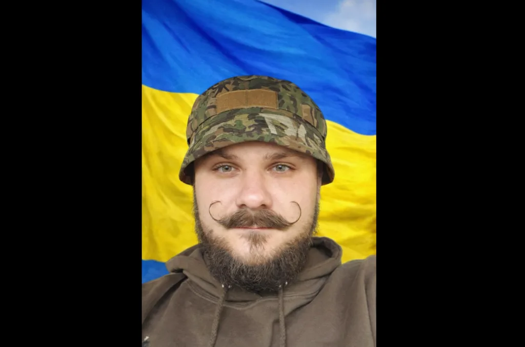 Військовий перед прапором України