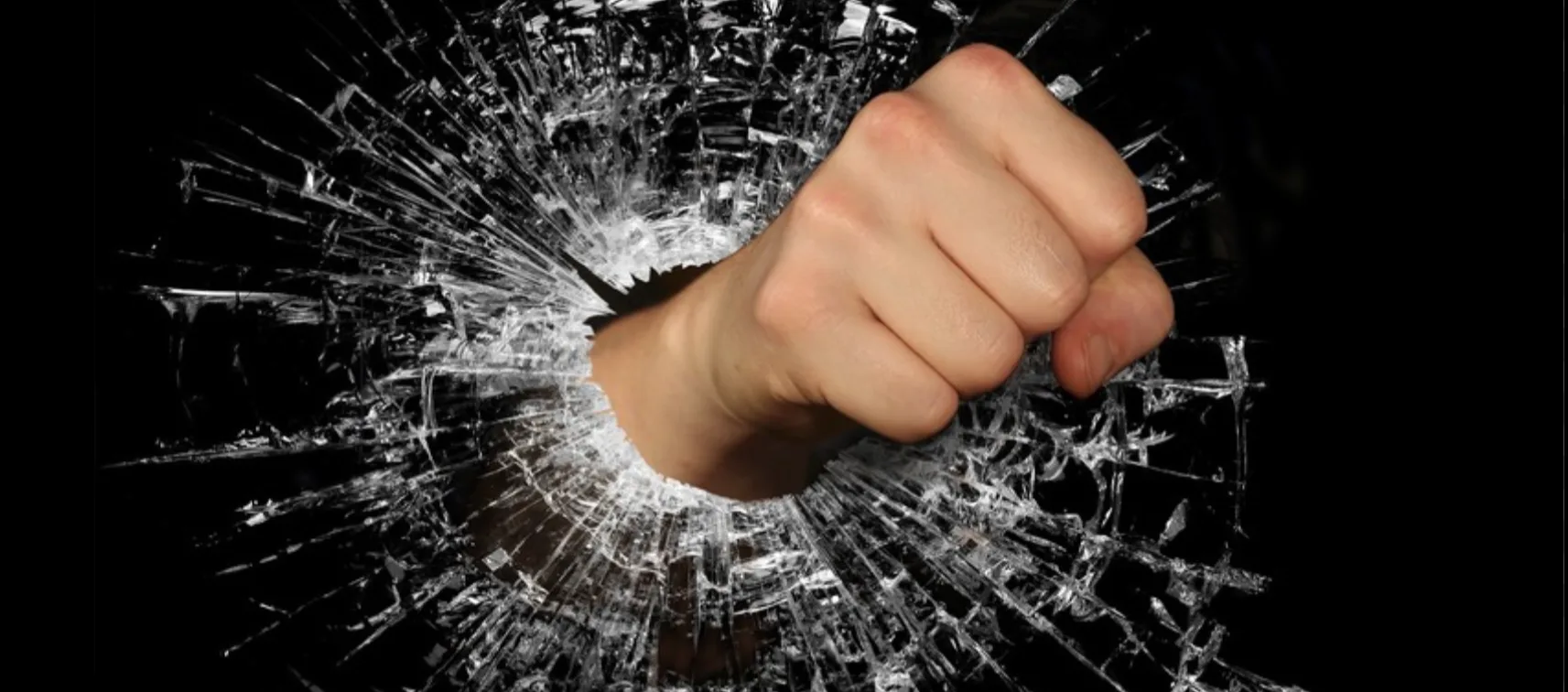 Кулак розбиває скло на чорному фоні