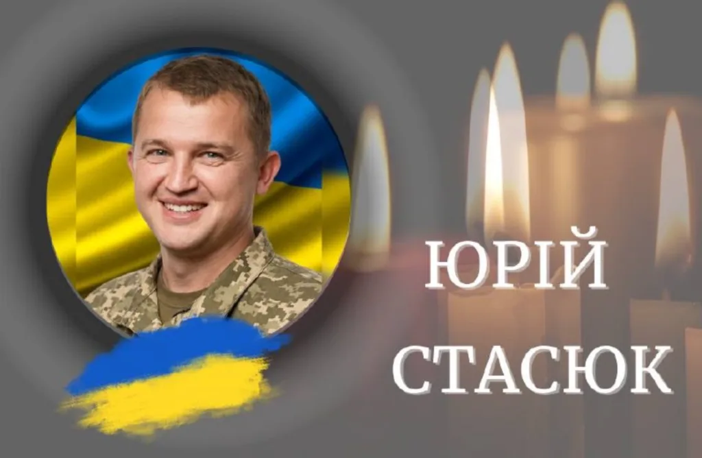 Фото військового на тлі прапора України та свічок