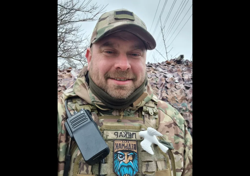 Військовий у камуфляжі з рацією та емблемою