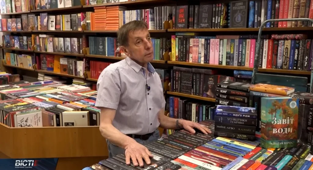 Чоловік у книжковому магазині серед полиць із книгами