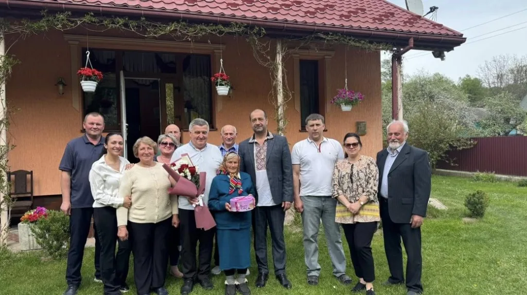 Група людей позує перед будинком у саду