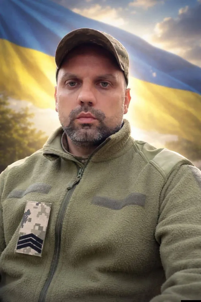 Військовий перед прапором України на заході сонця