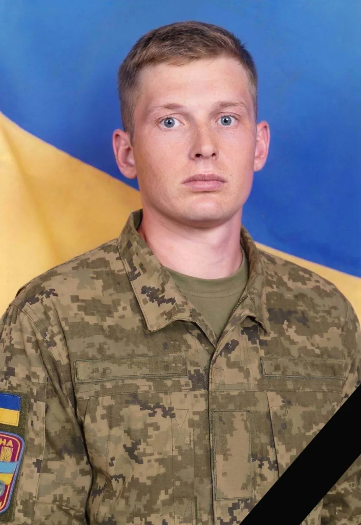 Український військовий у камуфляжі на тлі прапора
