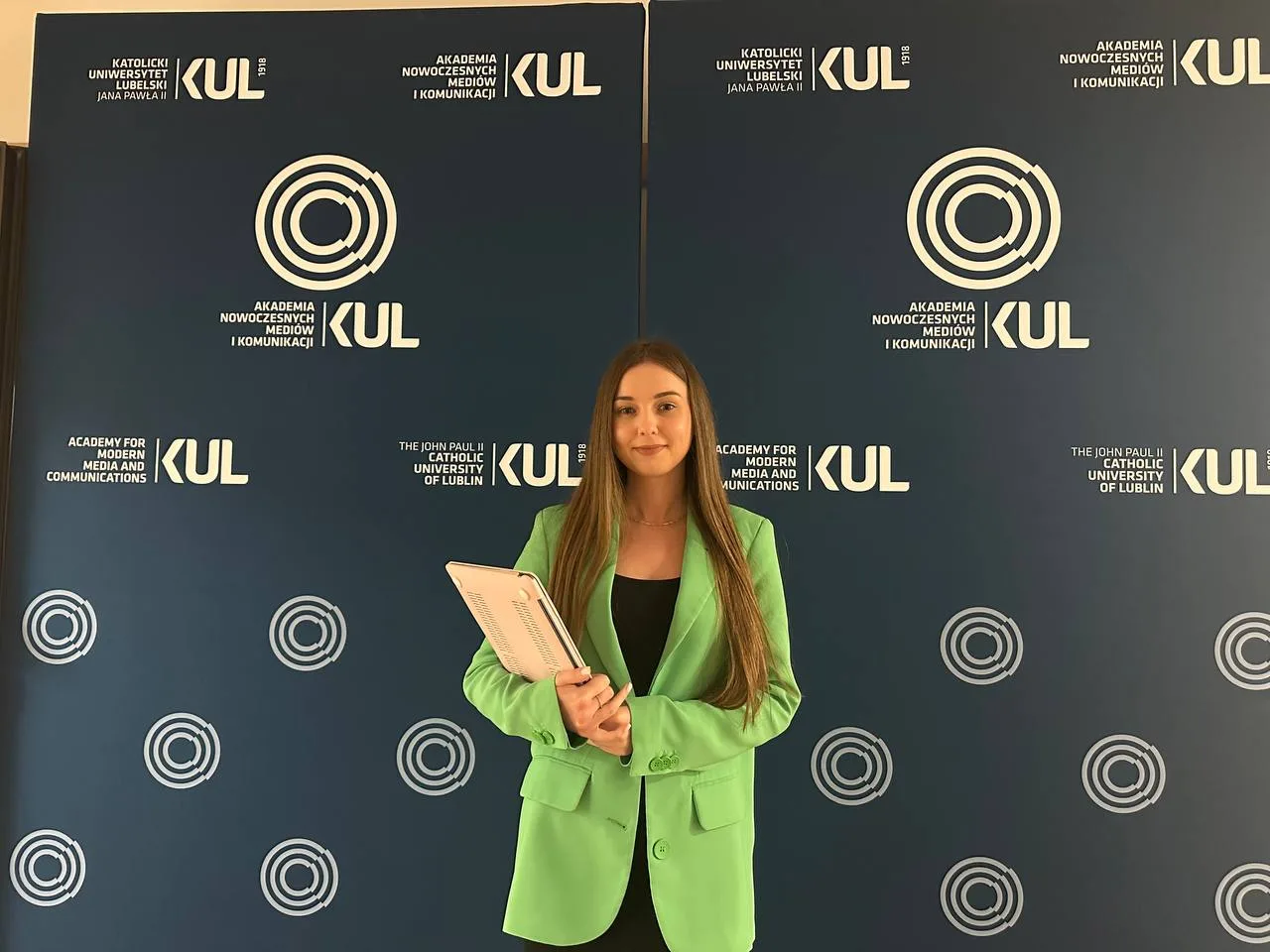 Жінка на фоні логотипів університету KUL
