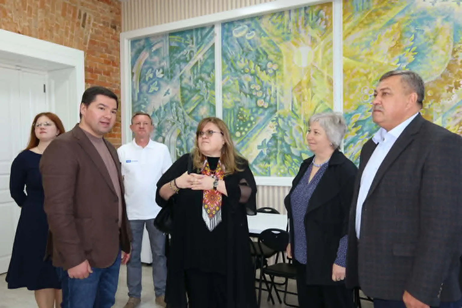 Група людей під час зустрічі біля картини