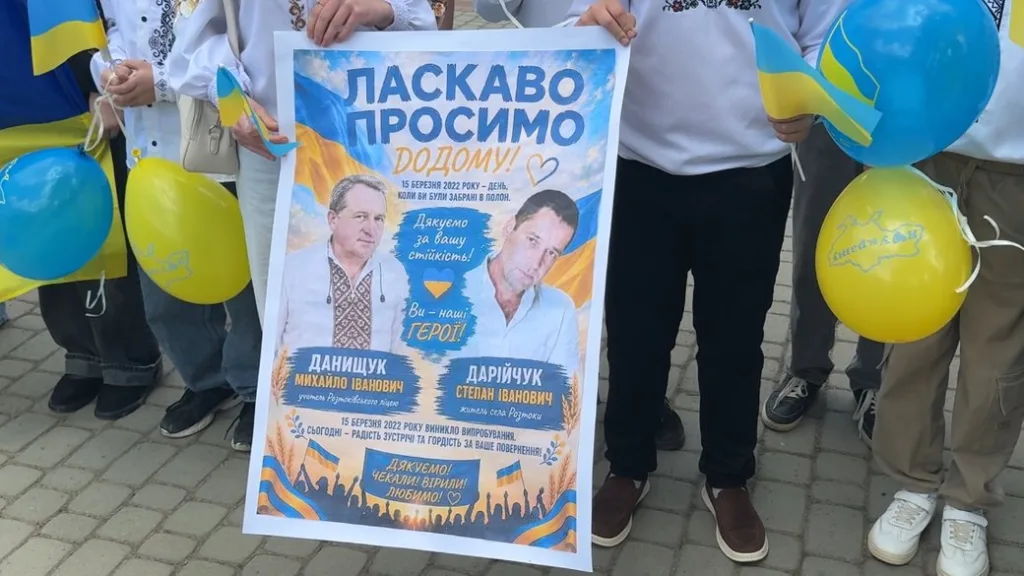 Люди тримають плакат із написом Ласкаво просимо додому