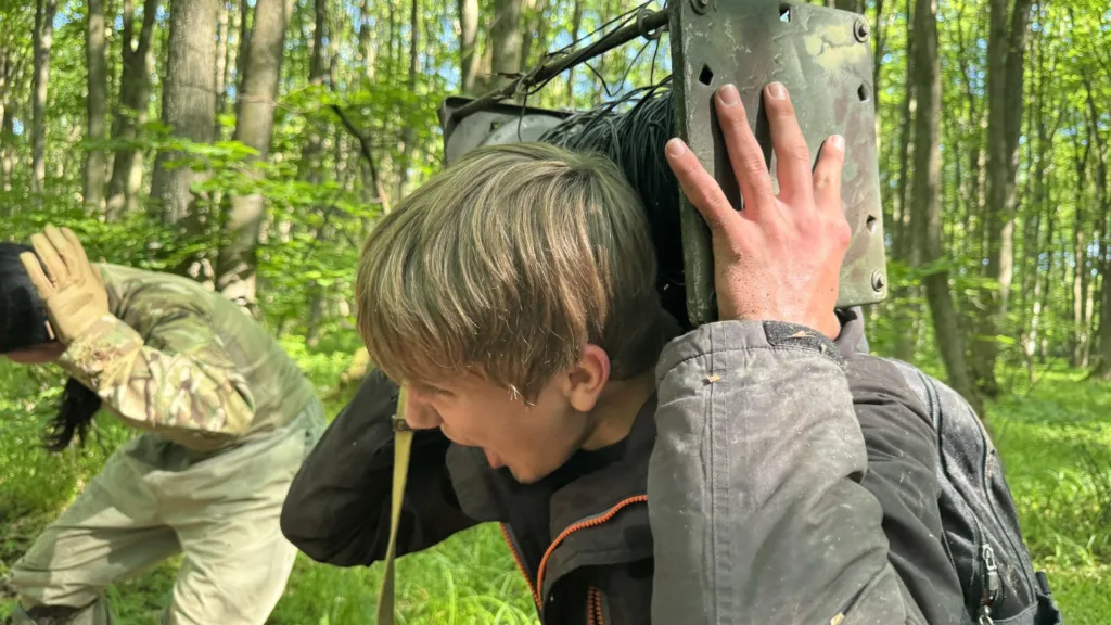 Люди несуть важке спорядження через ліс