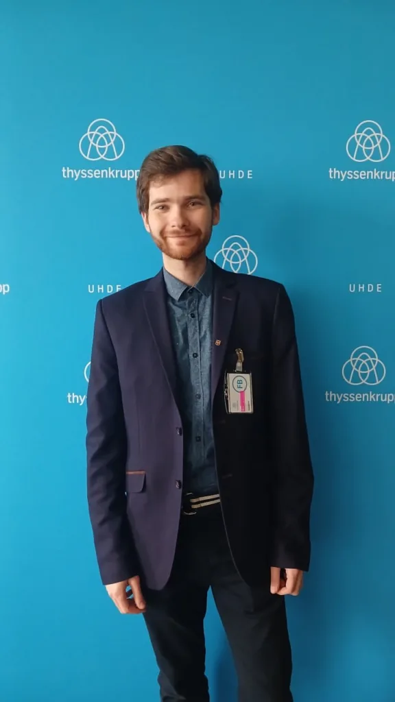 Чоловік у діловому одязі перед логотипом Thyssenkrupp