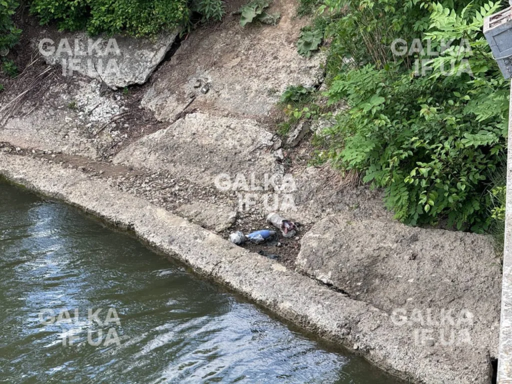 Берег річки з бетонними плитами та сміттям
