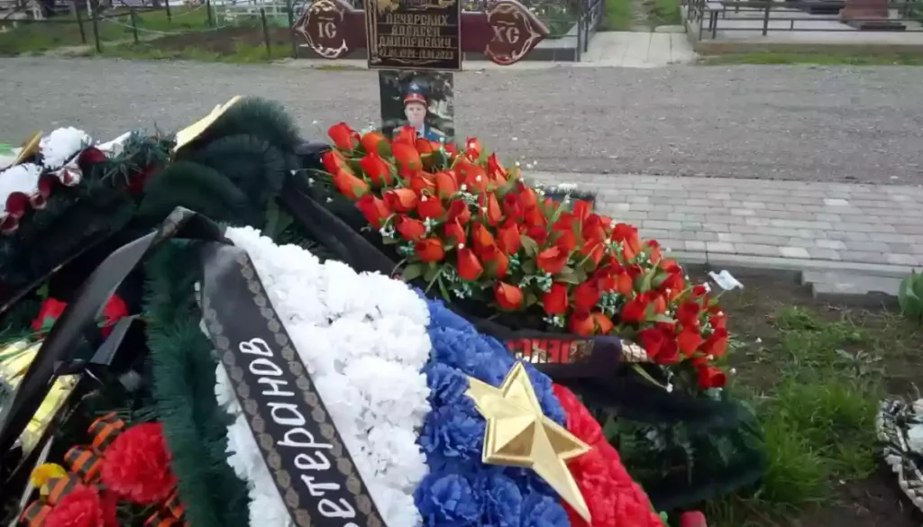 Квіткові вінки та надгробний хрест на цвинтарі