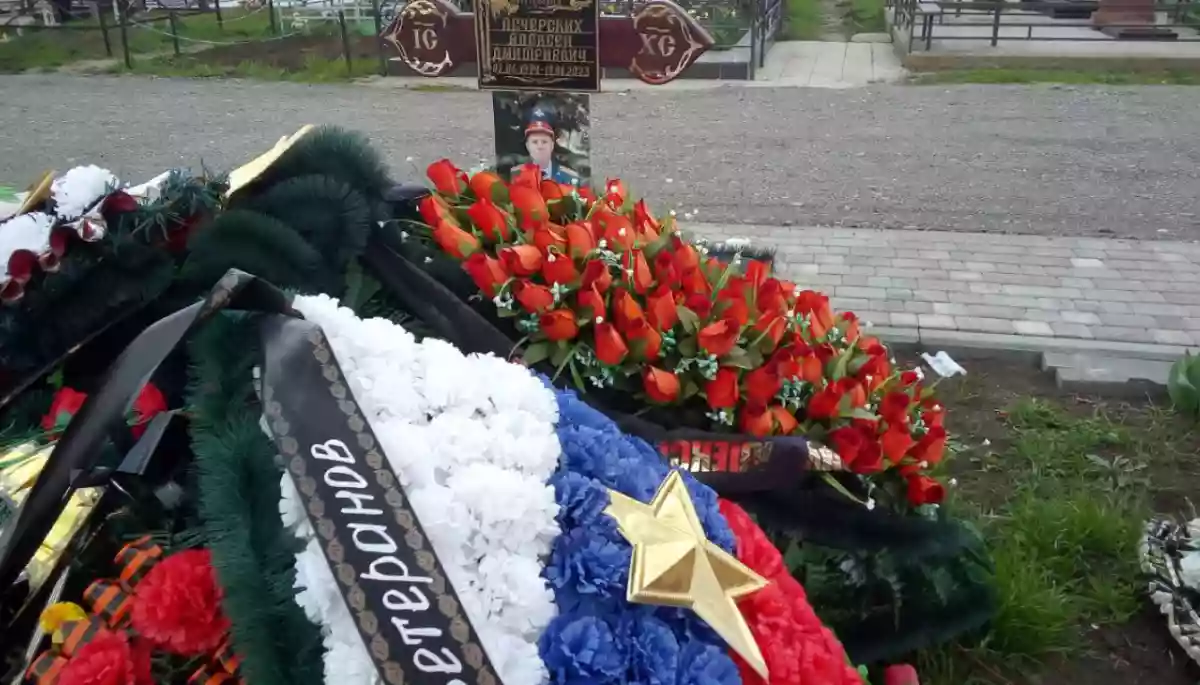 Квіткові вінки та надгробний хрест на цвинтарі