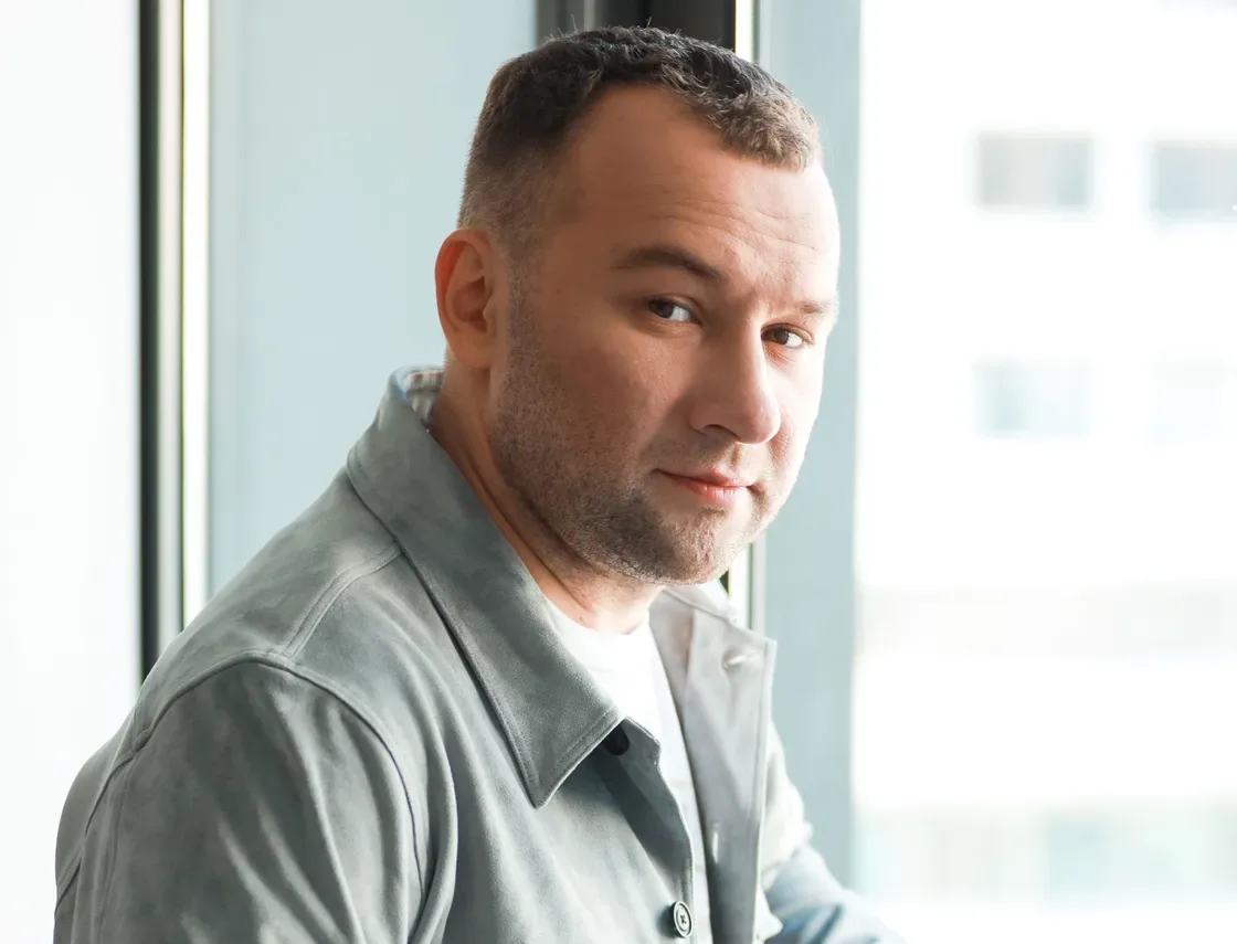 Чоловік у сірій сорочці біля вікна