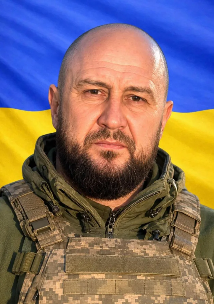 Військовий у формі перед прапором України