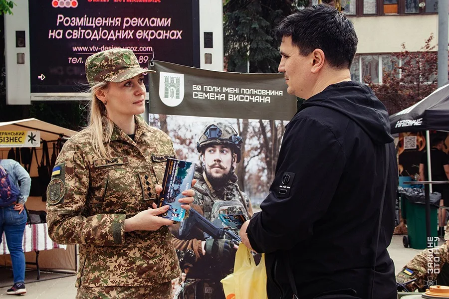 Військова спілкується з чоловіком на благодійному заході