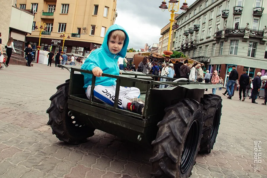 Дитина на іграшковому всюдиході на площі