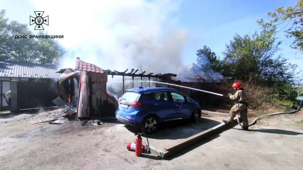 Пожежник гасить вогонь у гаражі біля авто