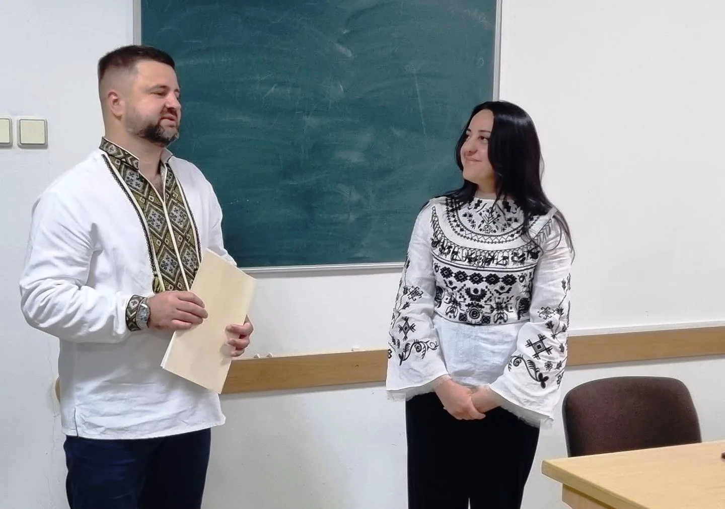 Люди у вишиванках стоять перед дошкою