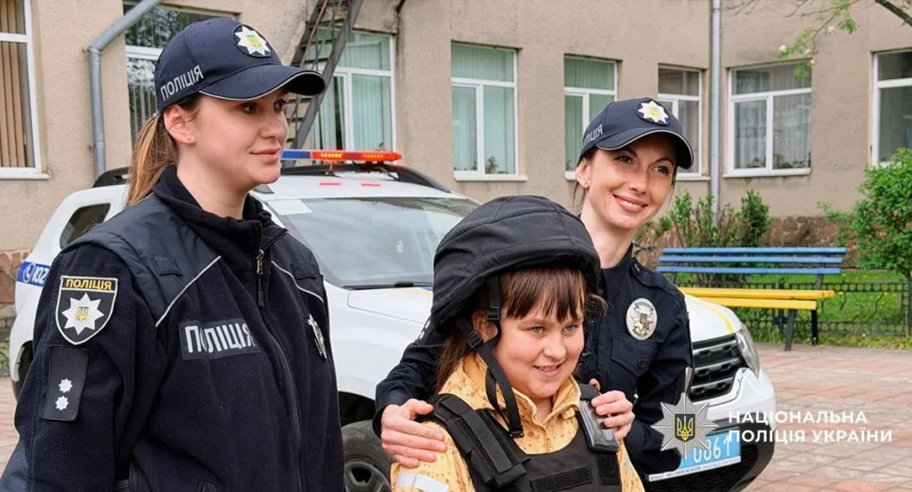 Поліцейські допомагають дитині одягнути бронежилет