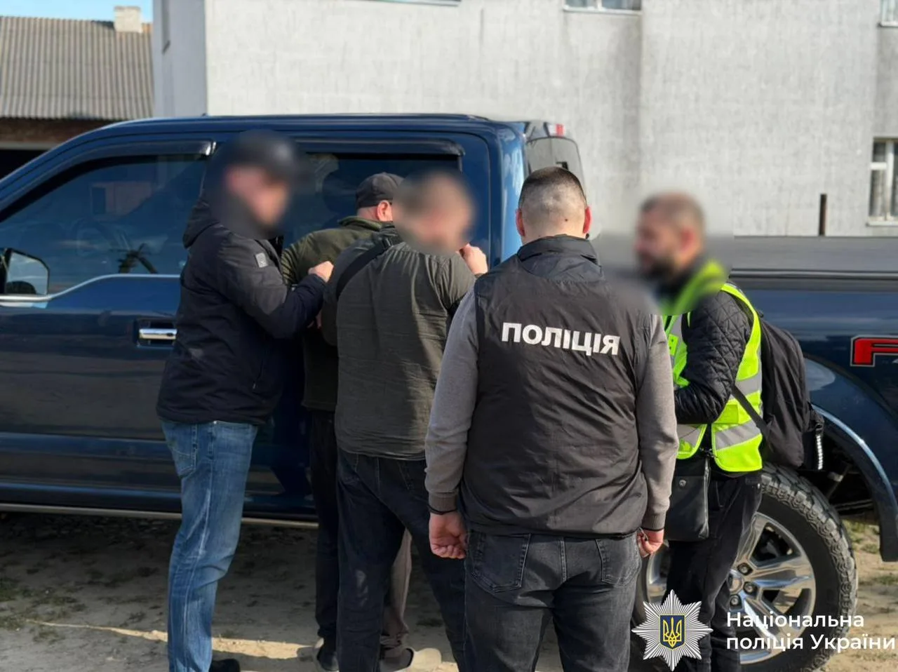 Поліцейські затримують чоловіка біля синього автомобіля
