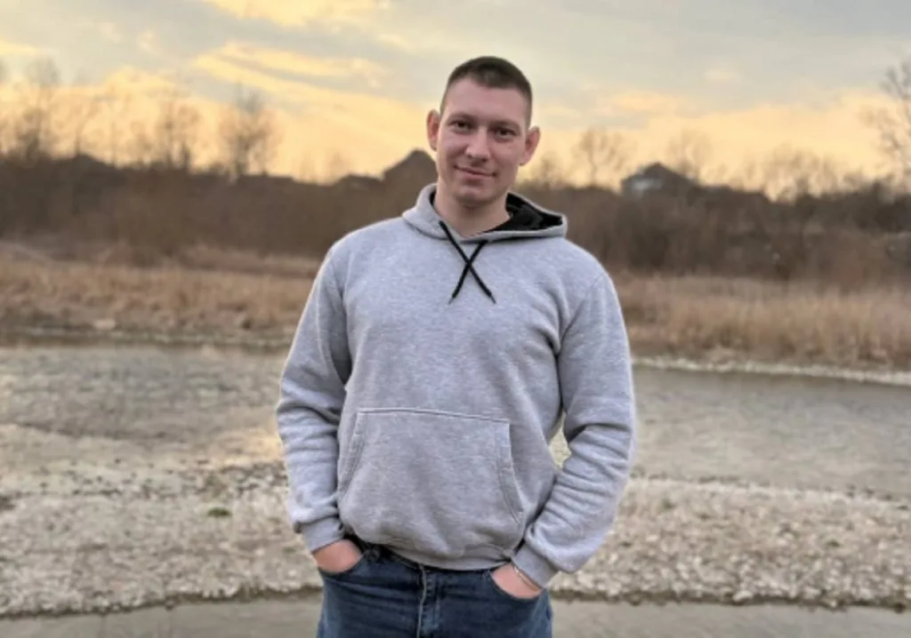 Чоловік у сірій толстовці на природі восени