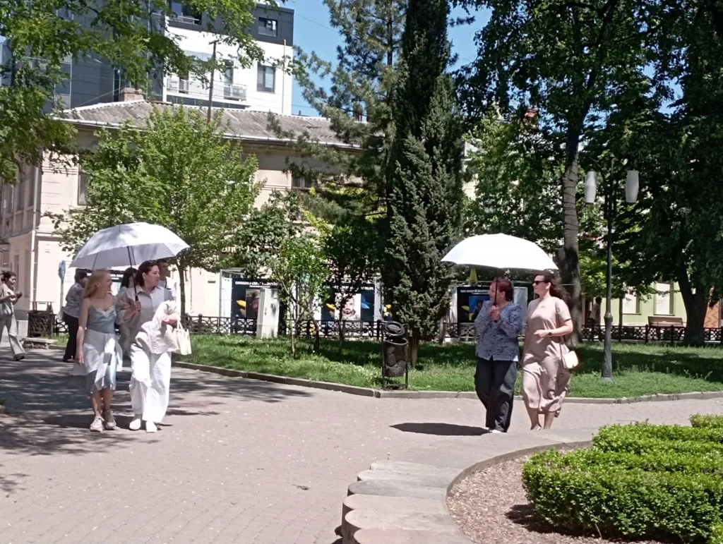 Люди гуляють парком із білими парасолями