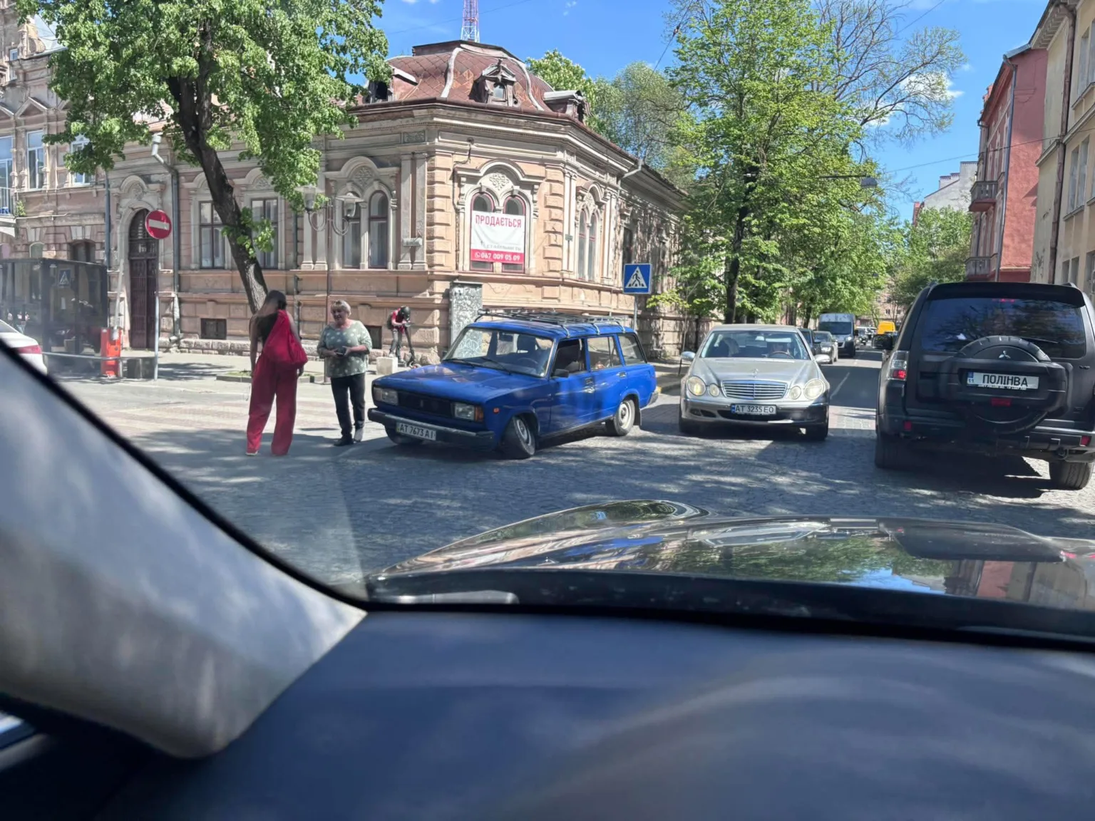 Дві людини розмовляють біля синього автомобіля на вулиці