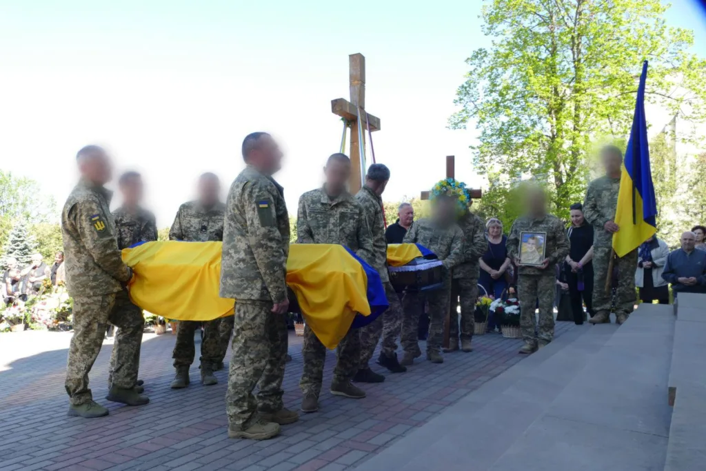 Військові несуть труну, накриту українським прапором
