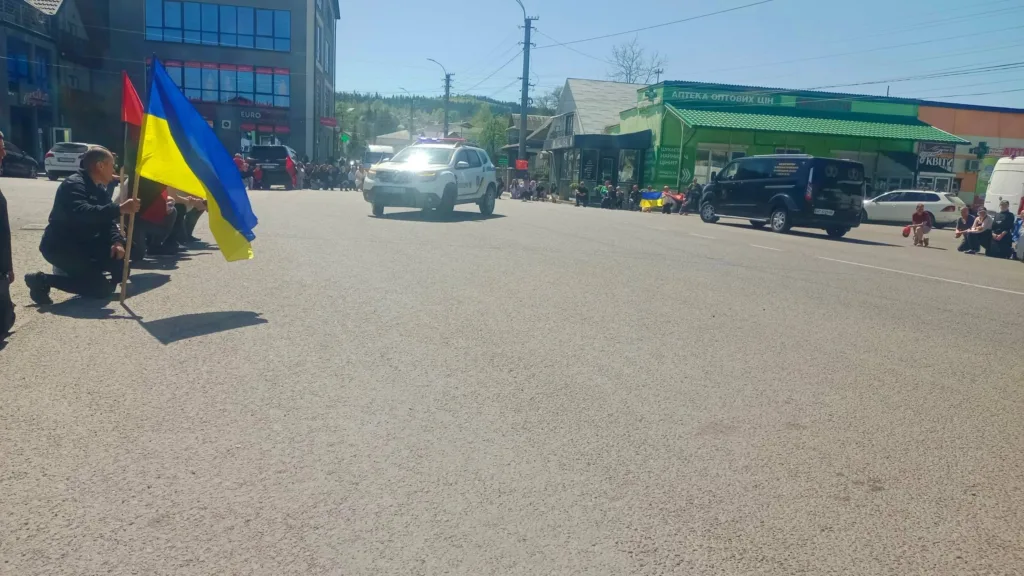 Люди на колінах з українським прапором на вулиці