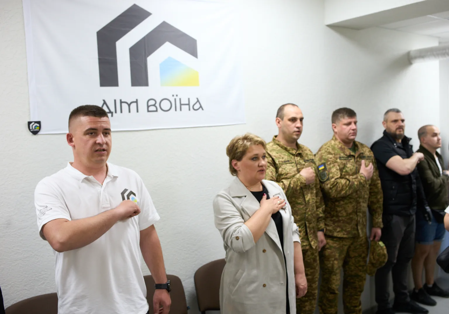 Люди стоять перед прапором Дім Воїна