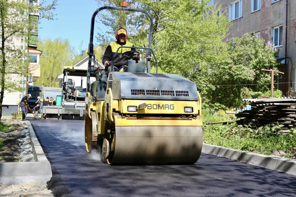 Робітники укладають гарячий асфальт дорожнім катком