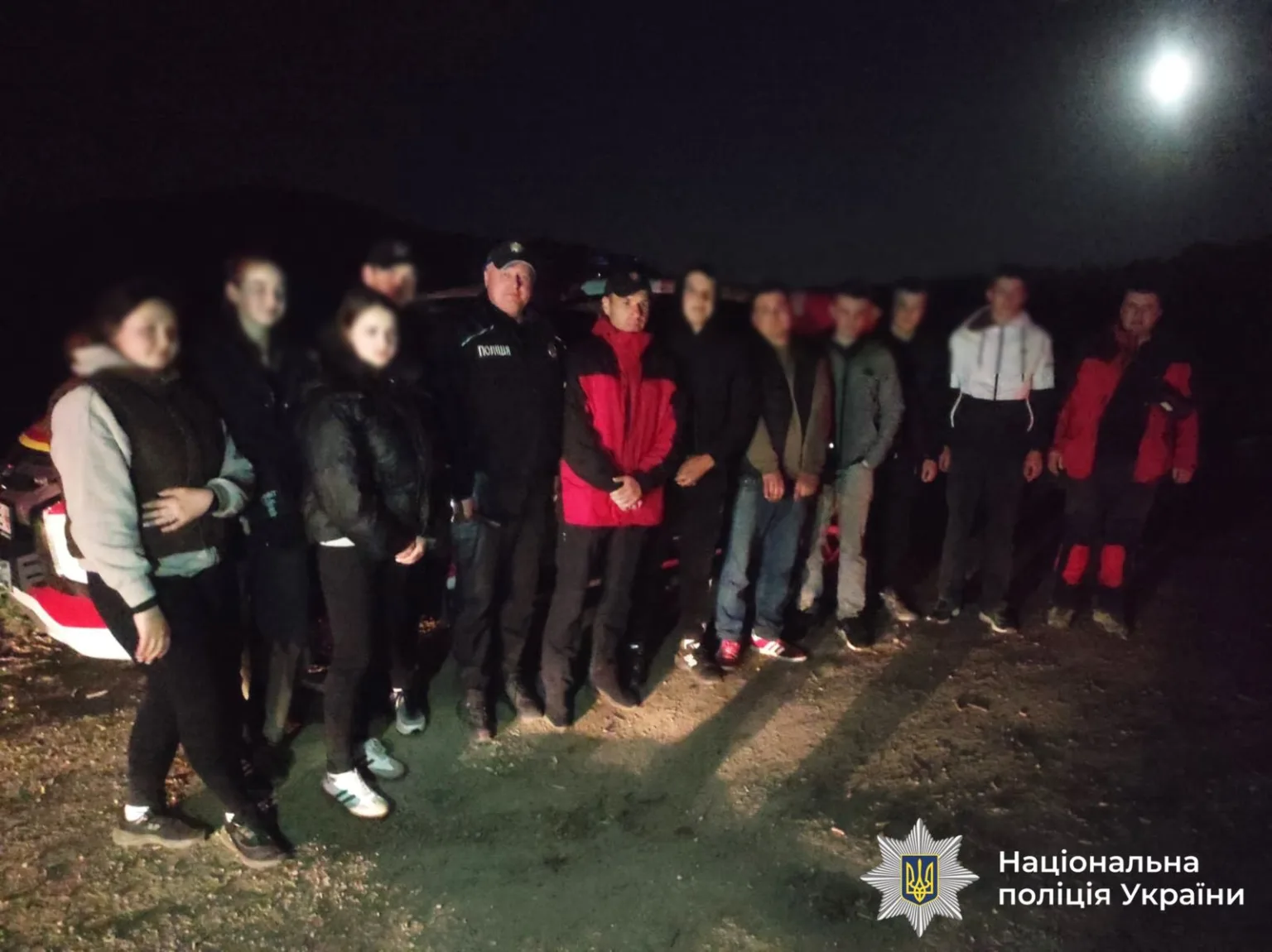 Група людей і поліція вночі під місяцем