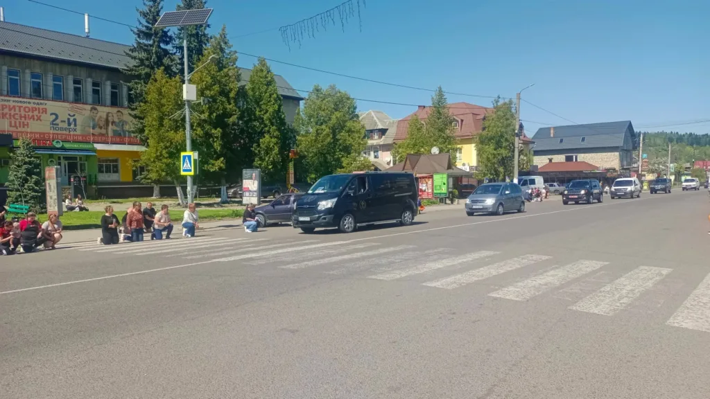 Люди стоять на колінах біля дороги