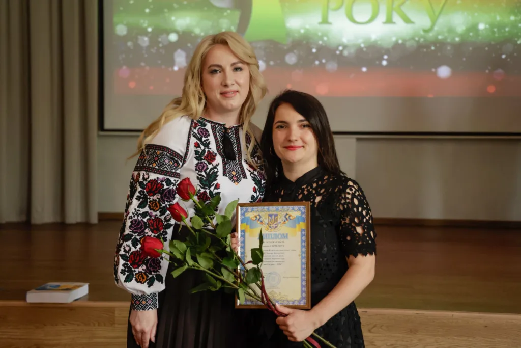 Жінки з квітами та дипломом на сцені