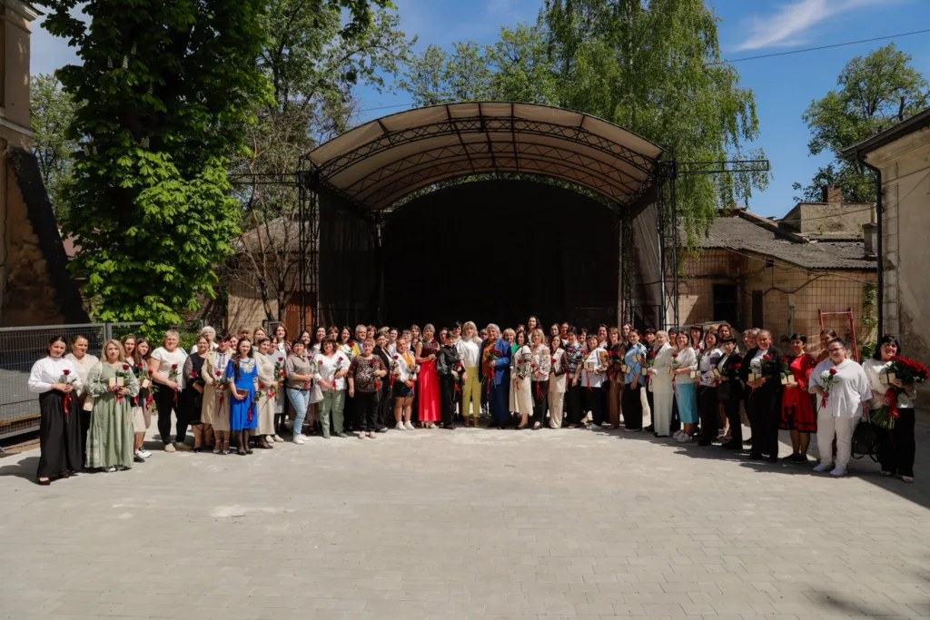 Група людей із квітами перед сценою на вулиці