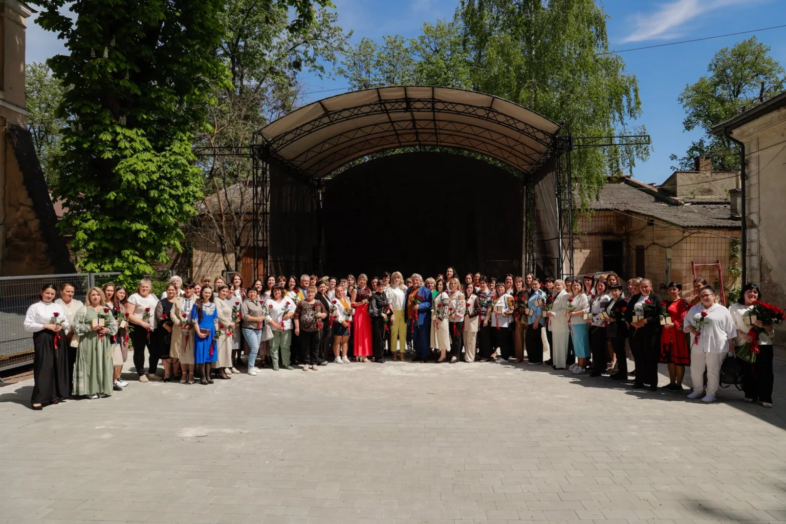 Група людей із квітами перед сценою на вулиці