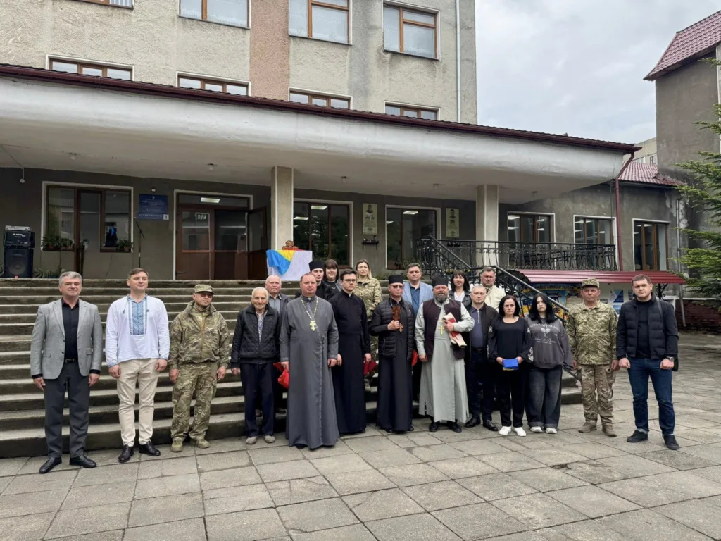 Група людей перед будівлею з українським прапором