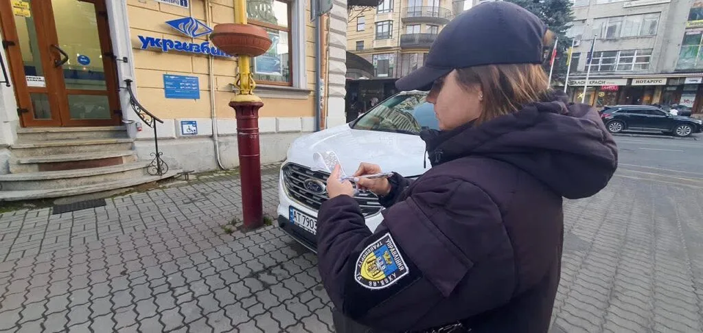 Інспектор пише штраф біля припаркованого автомобіля