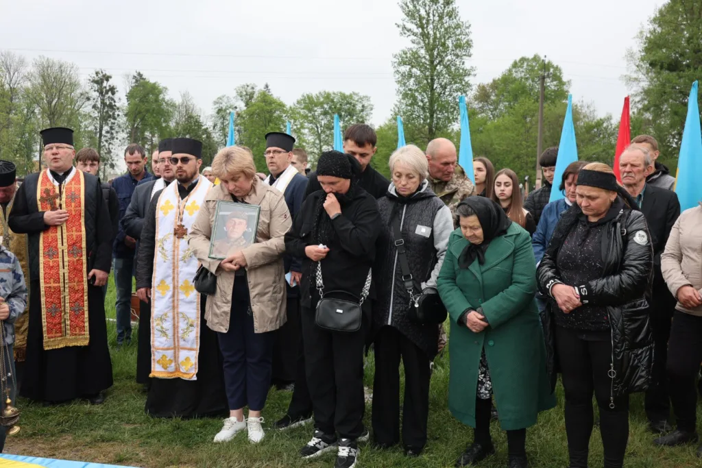 Люди на похороні воїна з синьо-жовтими прапорами