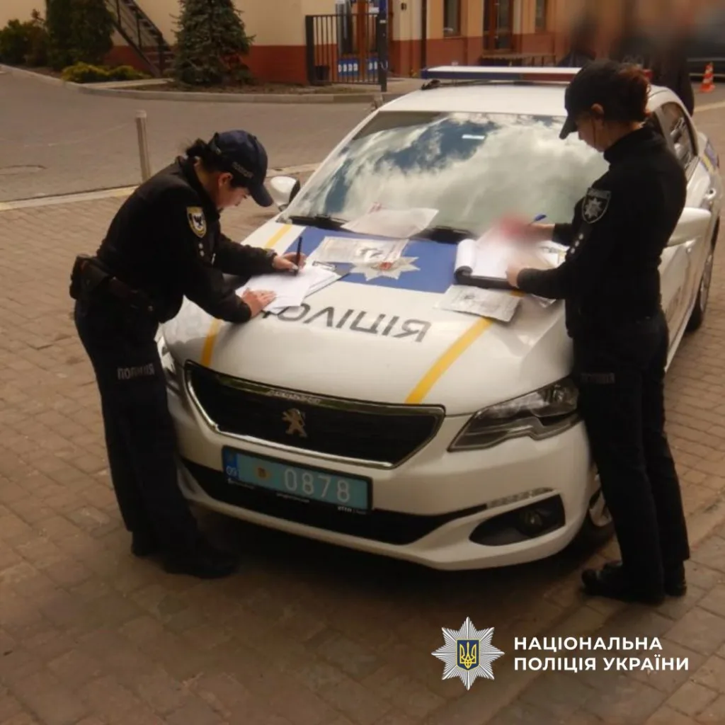 Поліцейські заповнюють документи на службовому авто