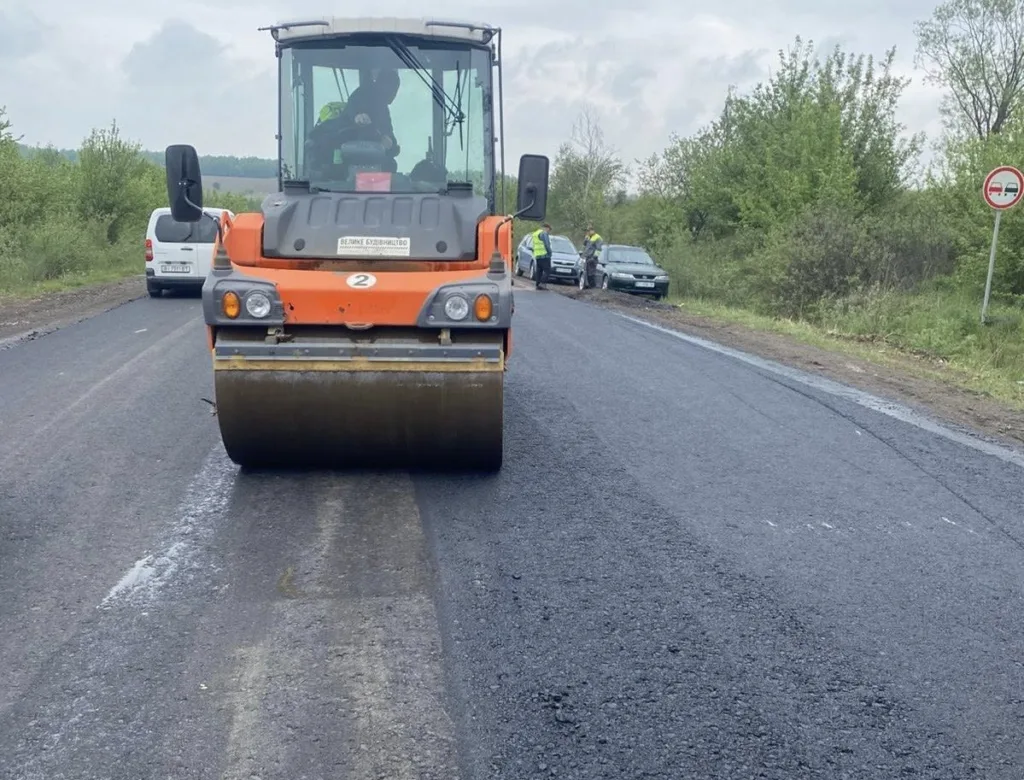 Дорожній каток ущільнює свіжий асфальт на трасі
