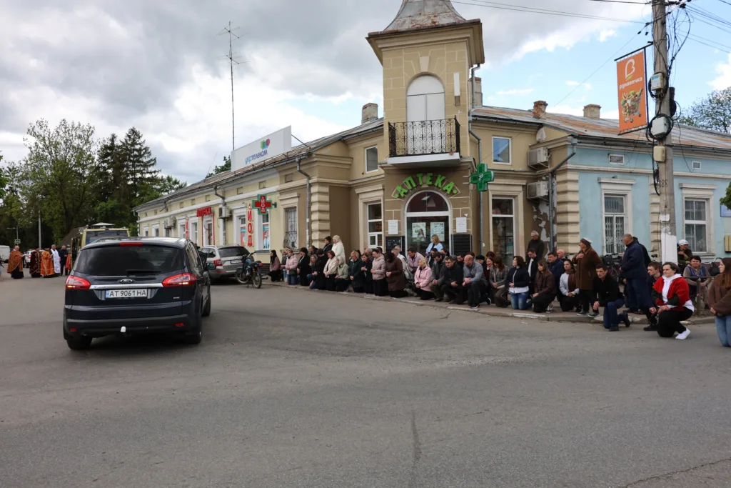 Люди стоять біля аптеки на міській вулиці