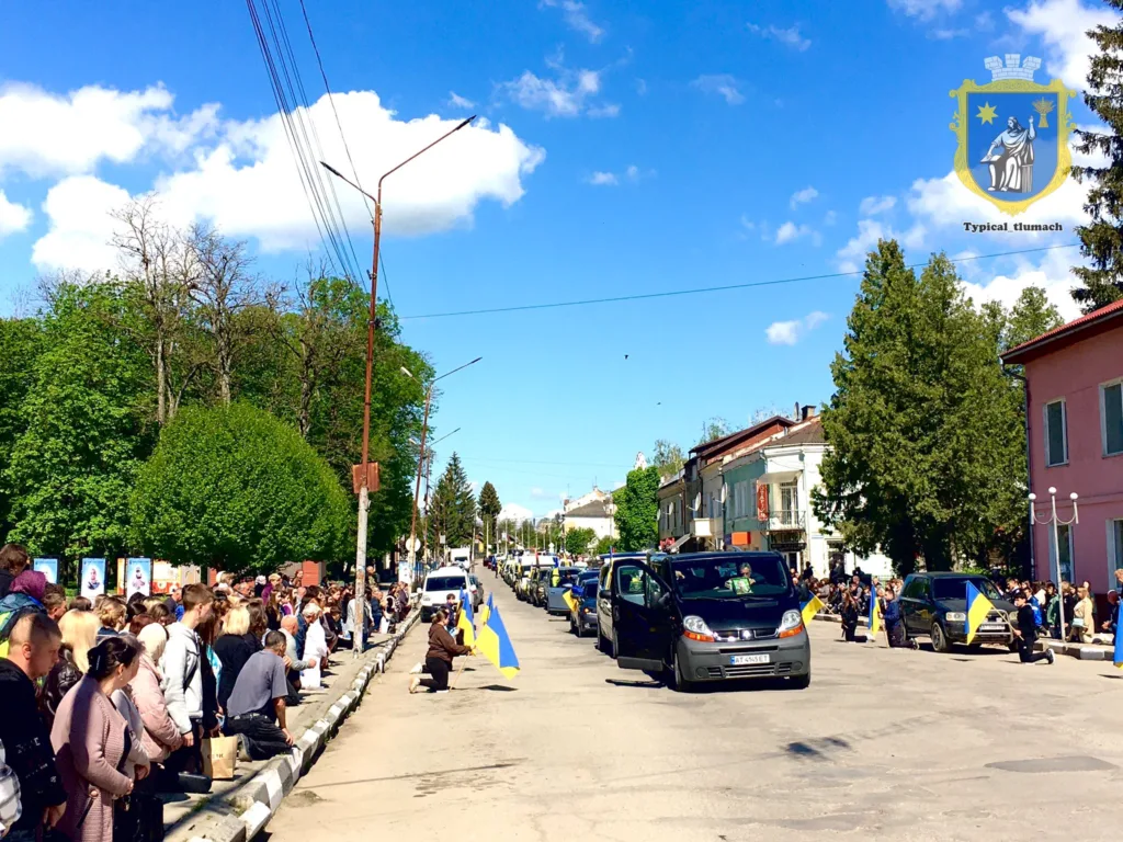 Люди стоять з українськими прапорами на вулиці