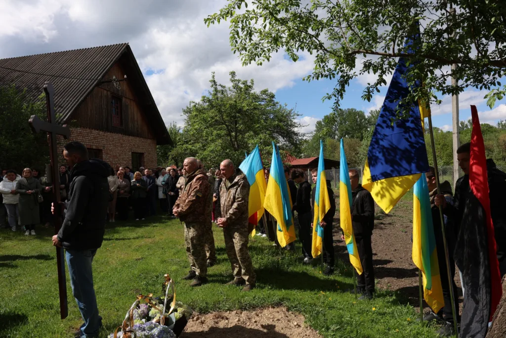 Похоронна церемонія з українськими прапорами на подвір’ї