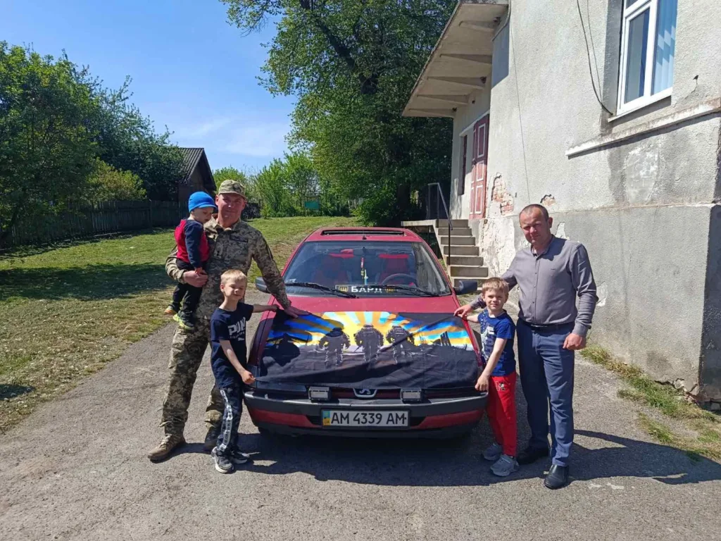 Люди біля автомобіля з патріотичним малюнком