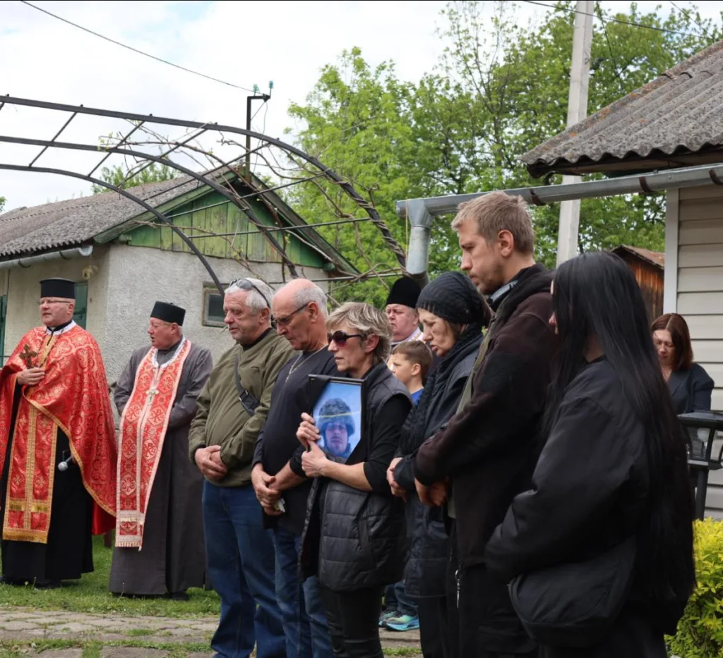 Люди на похороні воїна біля будинку