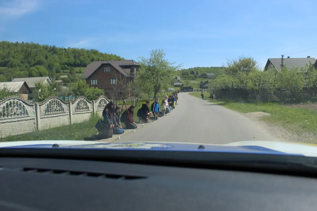 Люди стоять на колінах уздовж сільської дороги